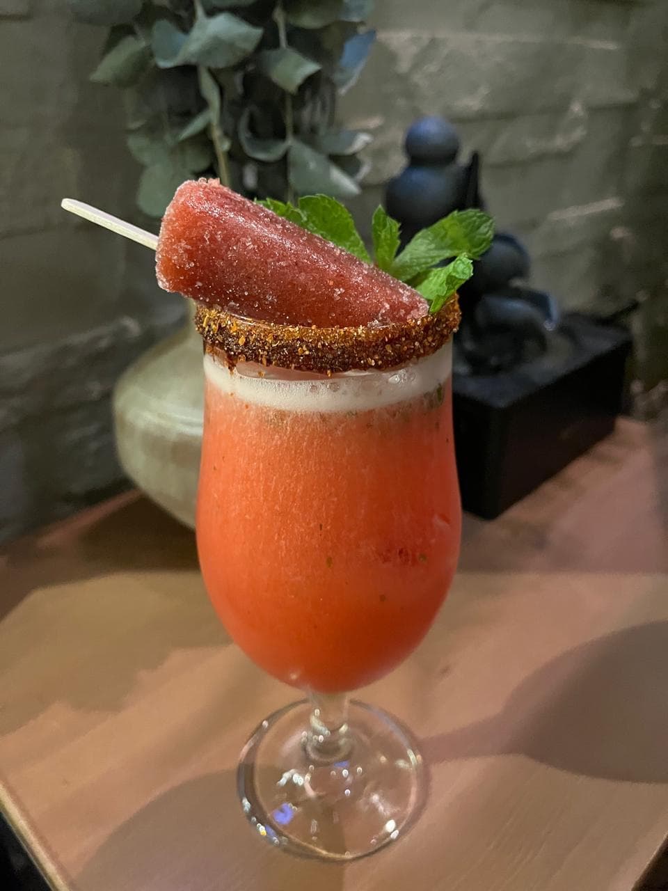 Coctel de sandía escarchado con chile-sal, decorado con una paleta de sandía y hierbabuena.