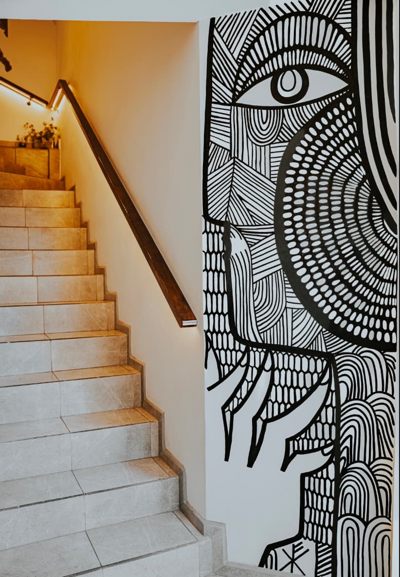 Escalera de la casa junto al mural en blanco y negro.