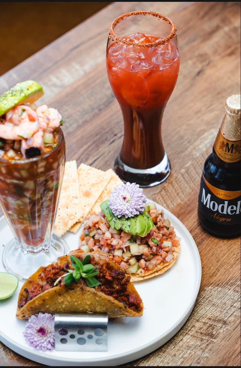 Coctel de camarón, tacos dorados con costra y tostada de ceviche, con una michelada escarchada y una cerveza Negra Modelo.