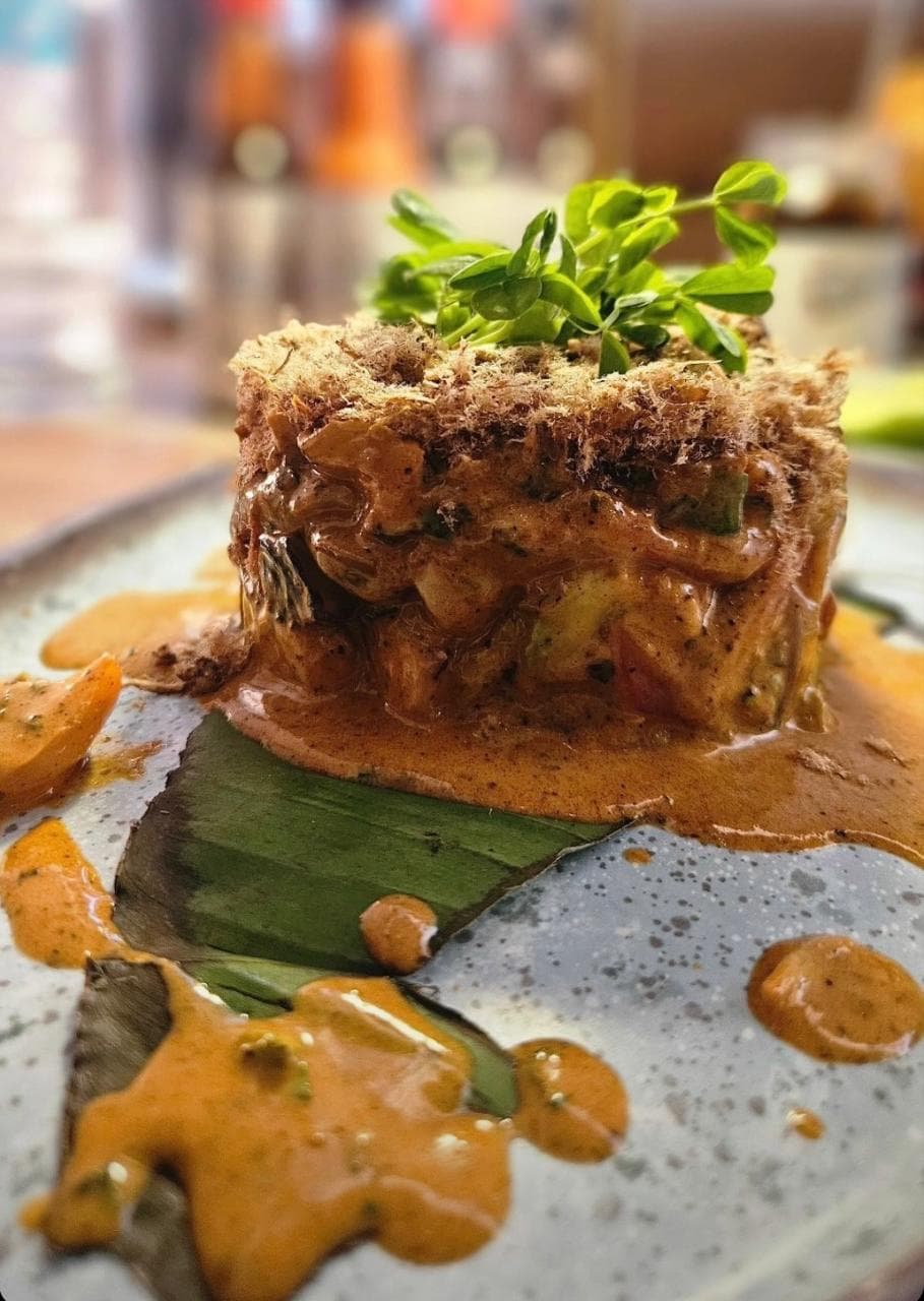 Tartar de mariscos con costra crujiente, bañado en aderezo especiado sobre hoja de plátano.